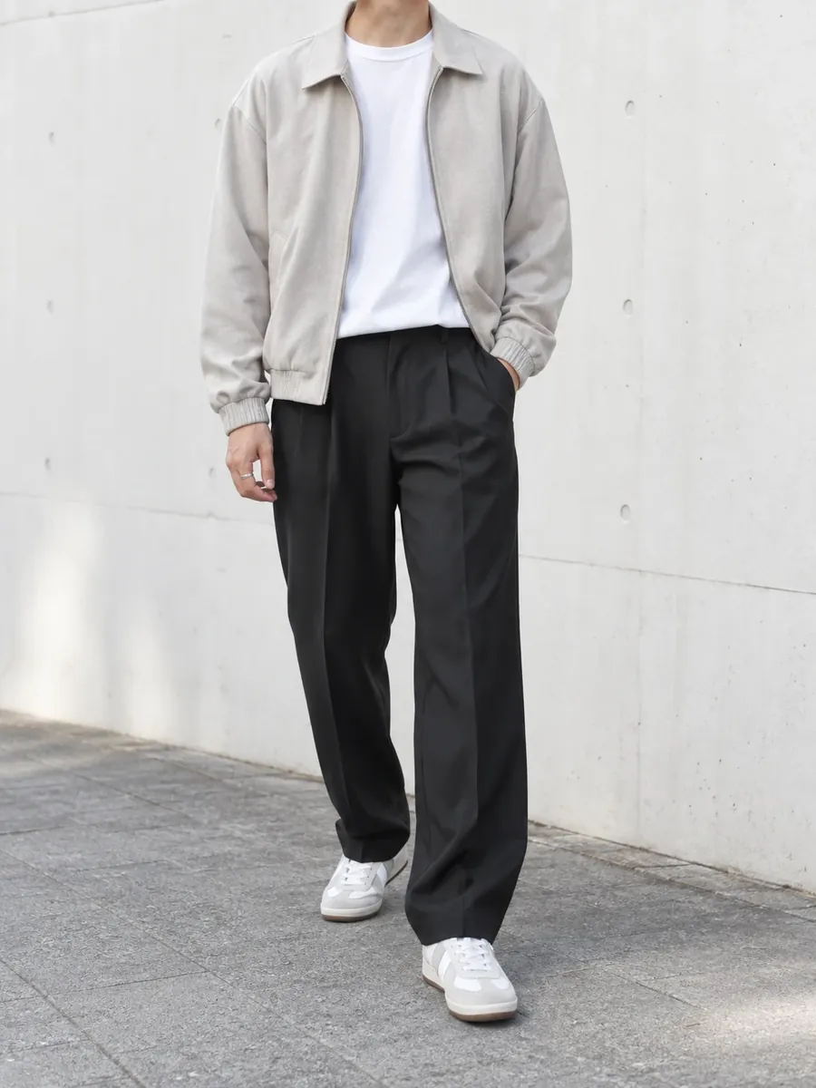 グレージュのブルゾンに白T、チャコールのスラックスと白いスニーカーを合わせた男性の服装